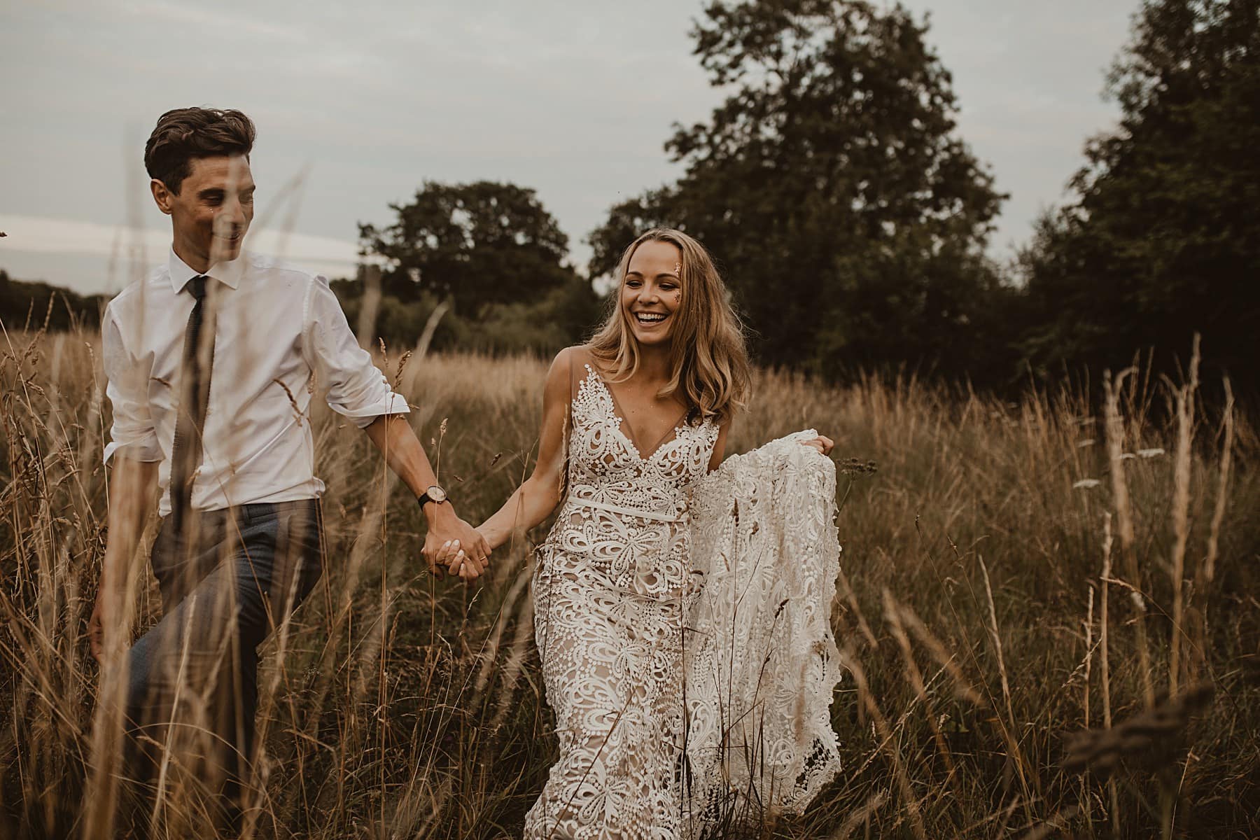Bride and Groom laughing and walking through meadow