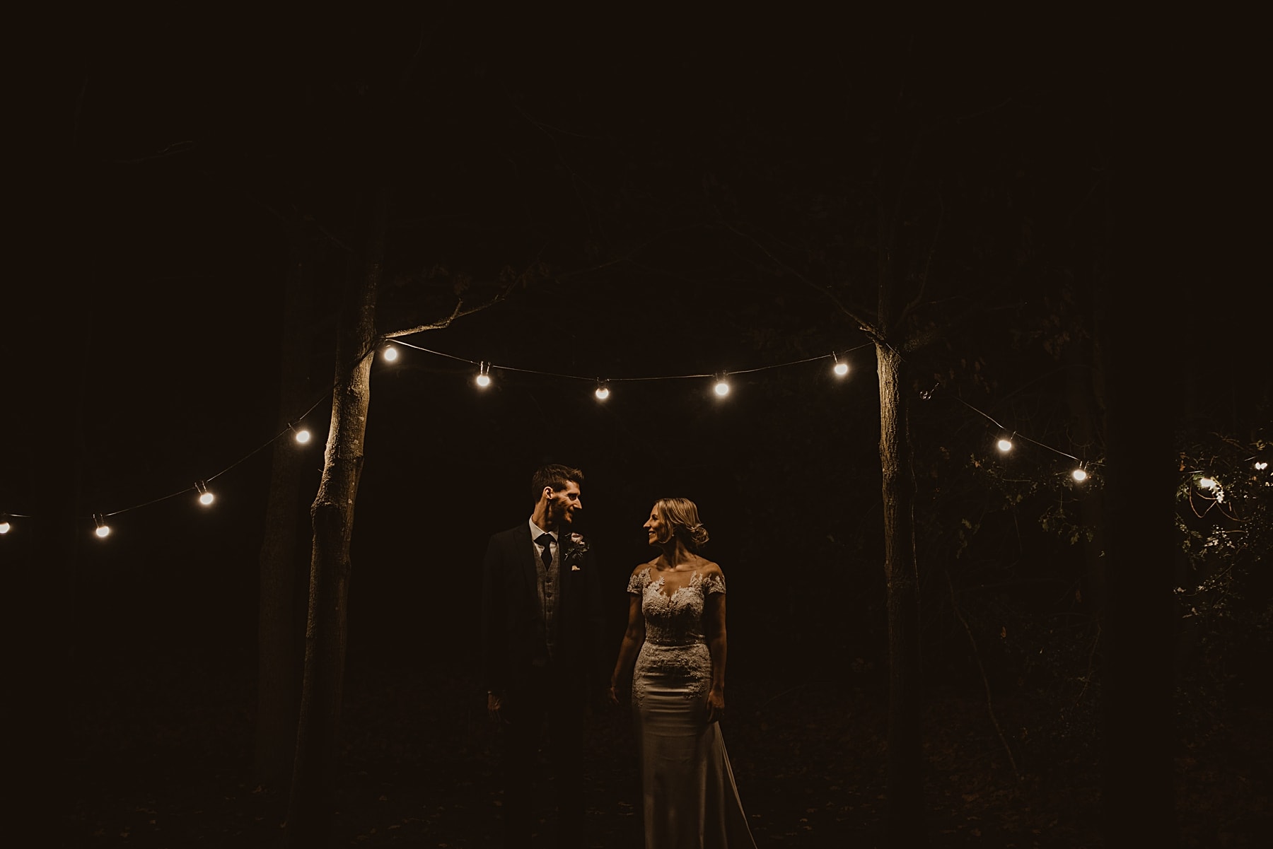 Couple standing under festoon lights