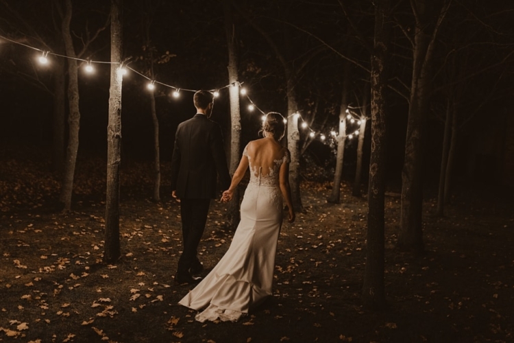 bride and groom walking through woods