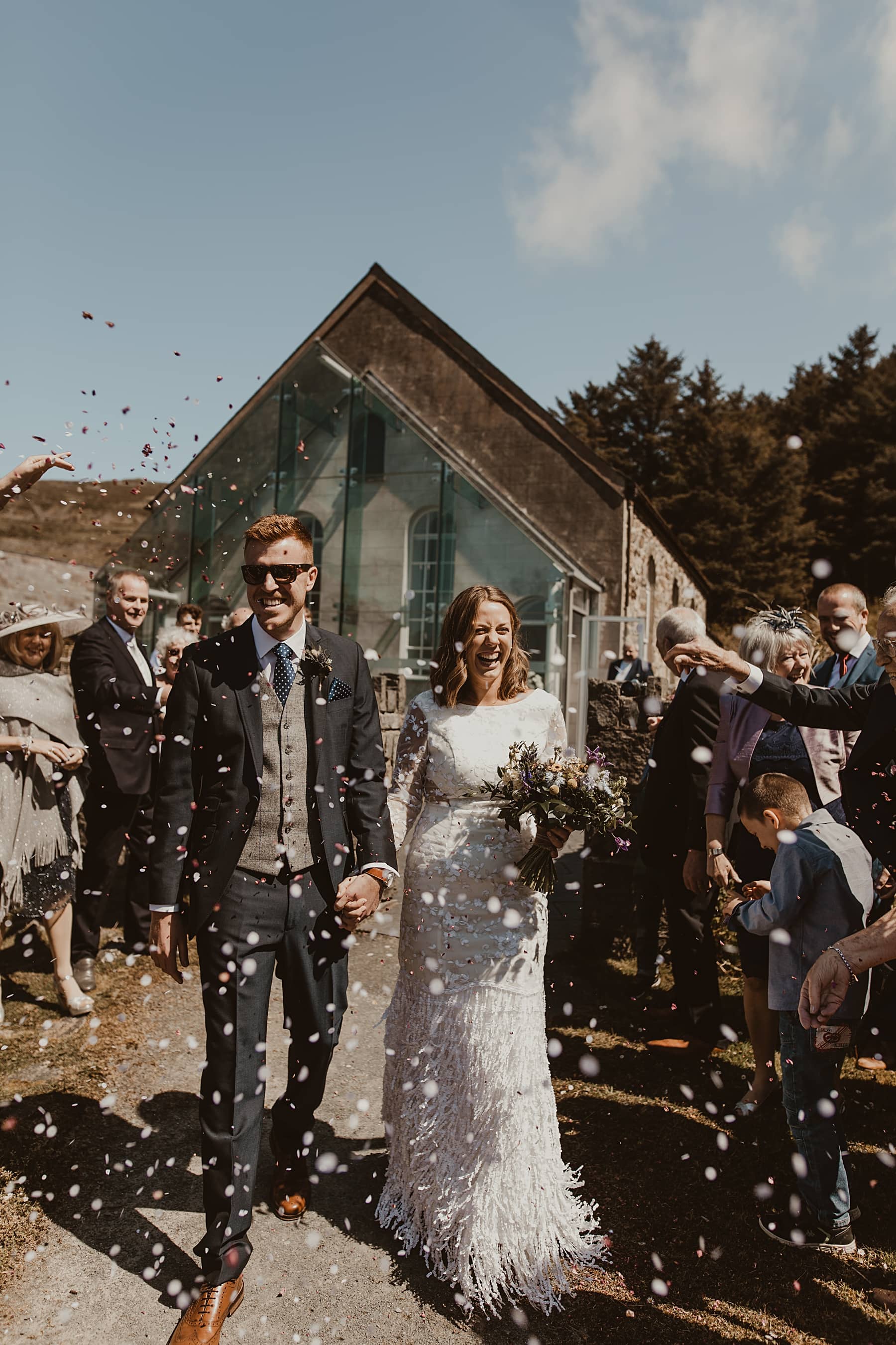 bride and groom walking and laughing through confetti