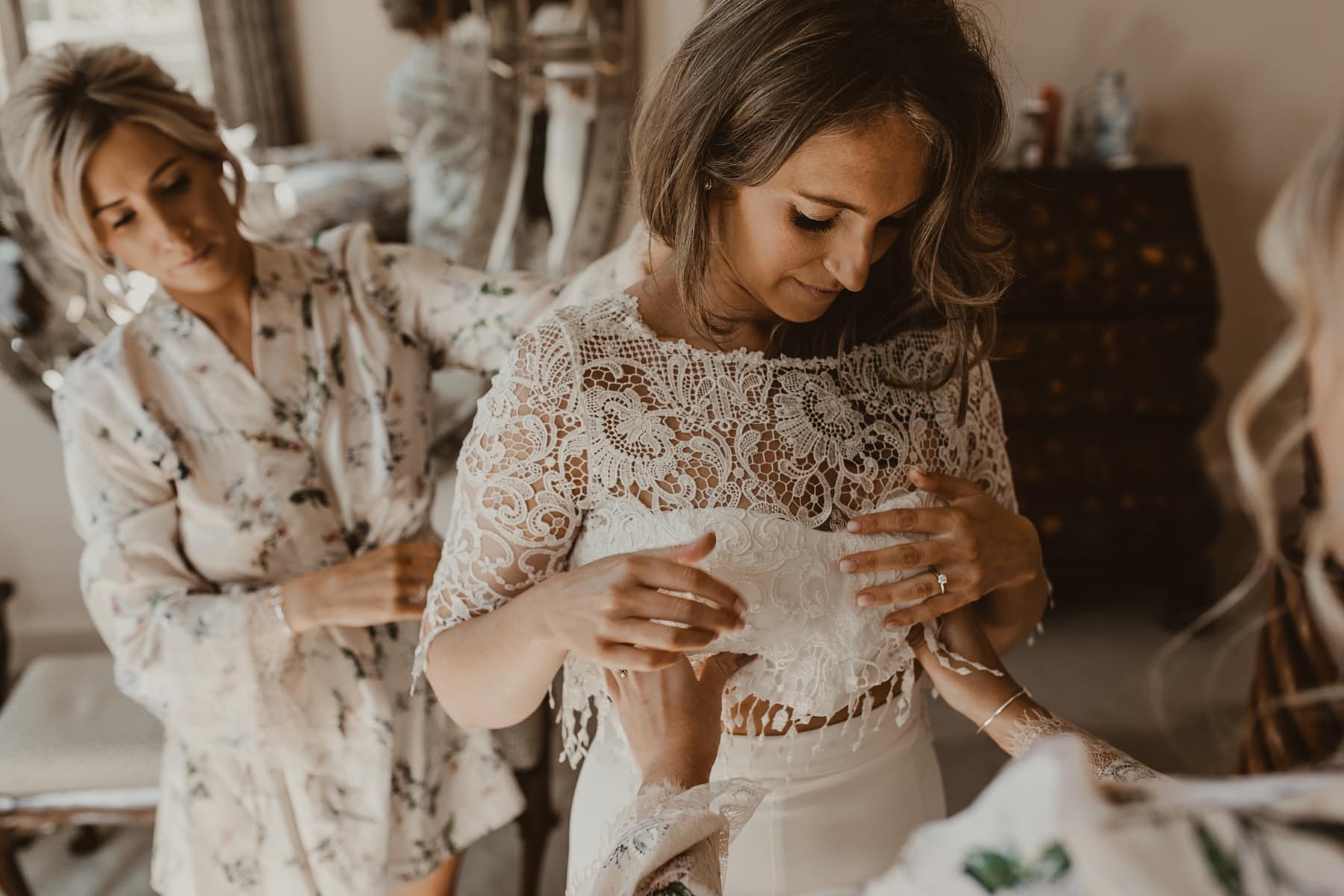 Bride putting two piece, lace wedding dress on